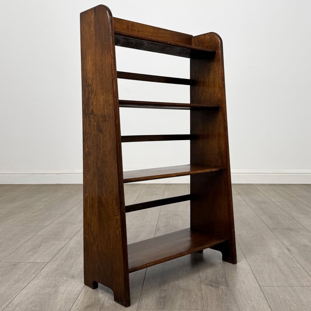 A freestanding early 20th-century warm brown open oak bookcase featuring three fixed shelves and solid side panels. View IX