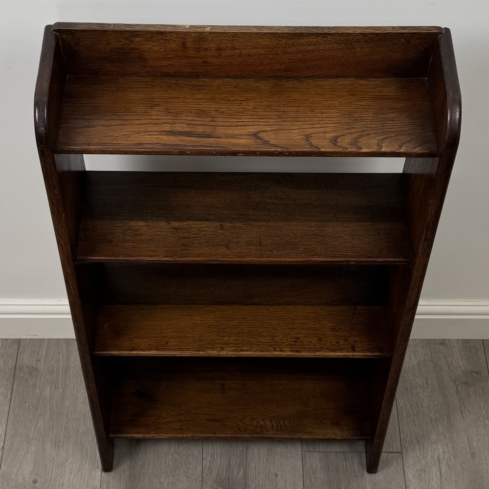A freestanding early 20th-century warm brown open oak bookcase featuring three fixed shelves and solid side panels. View X