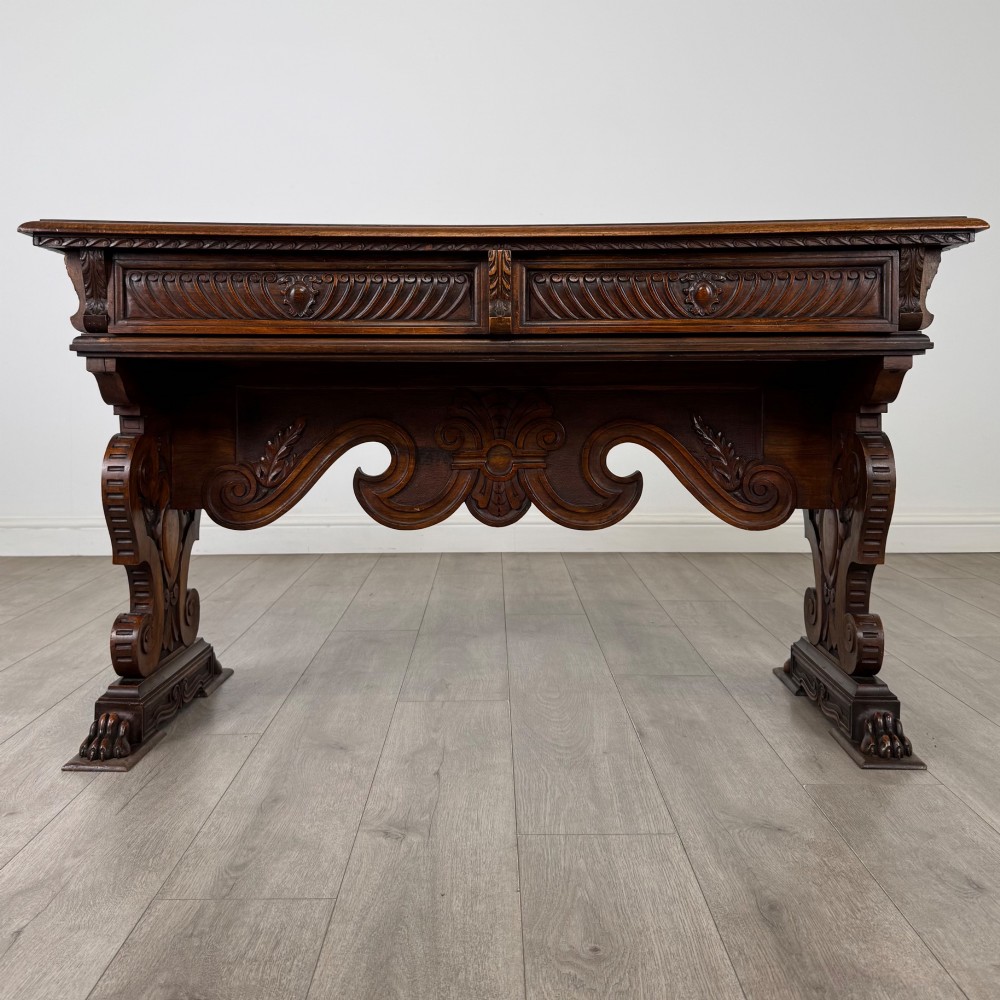 A 19th-century French-style carved walnut side table featuring two decorated drawers, scrolling legs, and paw feet.