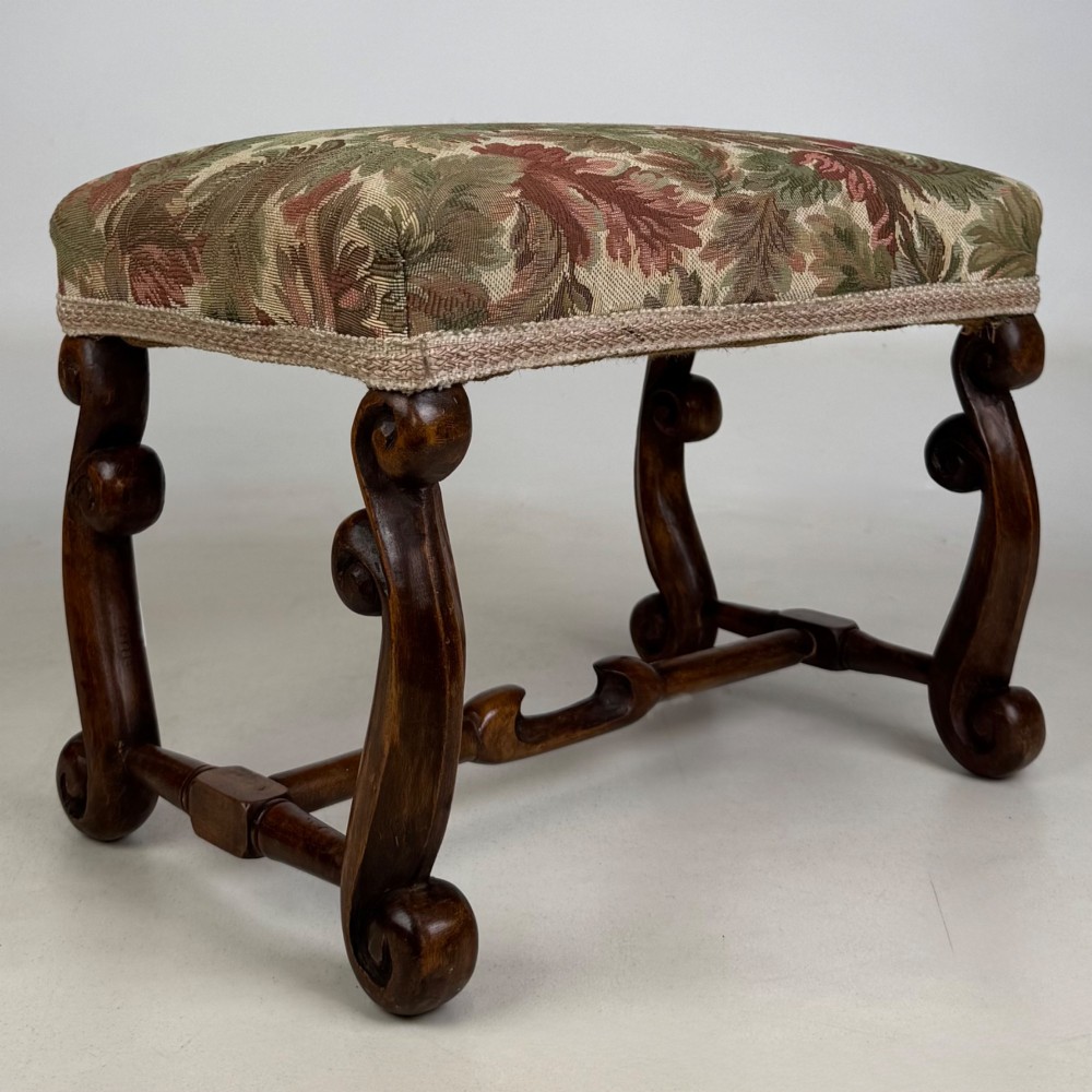 An Edwardian rectangular low stool featuring a carved dark walnut frame with scroll legs, an H-stretcher, and botanical tapestry upholstery. View VIII