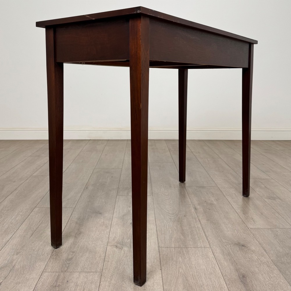 A dark mahogany writing table featuring two frieze drawers with brass swan-neck handles and tapered square legs. View IV