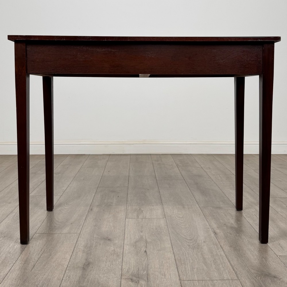 A dark mahogany writing table featuring two frieze drawers with brass swan-neck handles and tapered square legs. View V