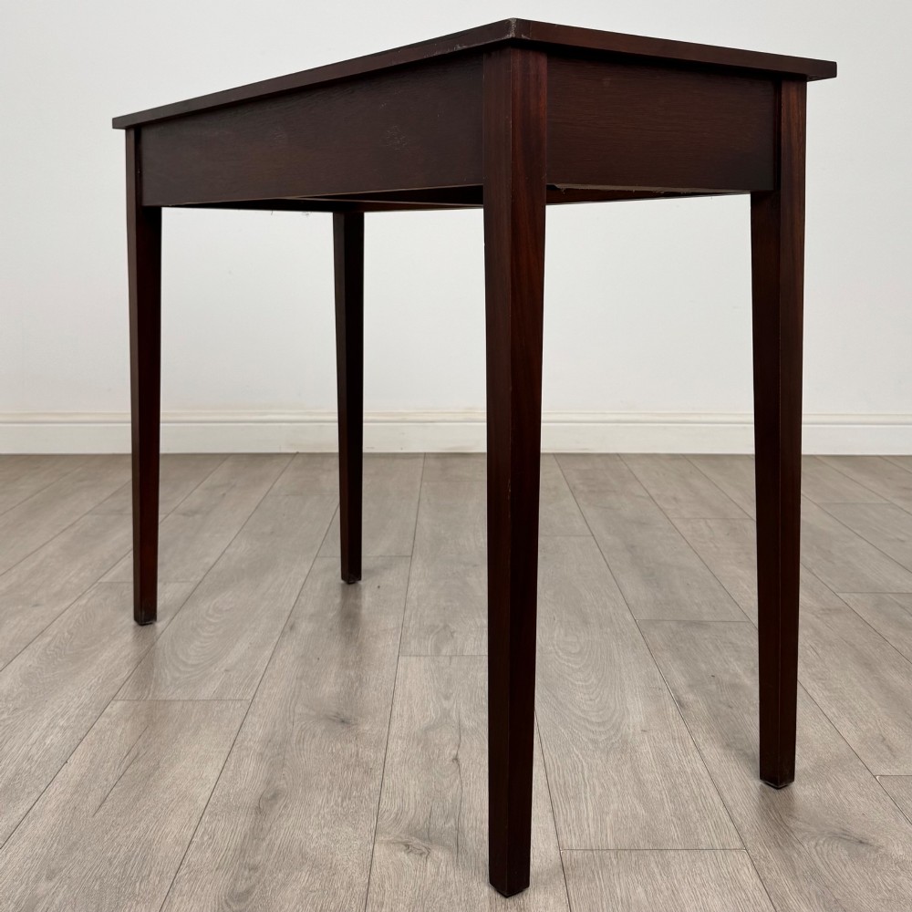 A dark mahogany writing table featuring two frieze drawers with brass swan-neck handles and tapered square legs. View VI