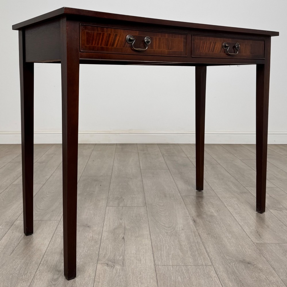 A dark mahogany writing table featuring two frieze drawers with brass swan-neck handles and tapered square legs. View VIII