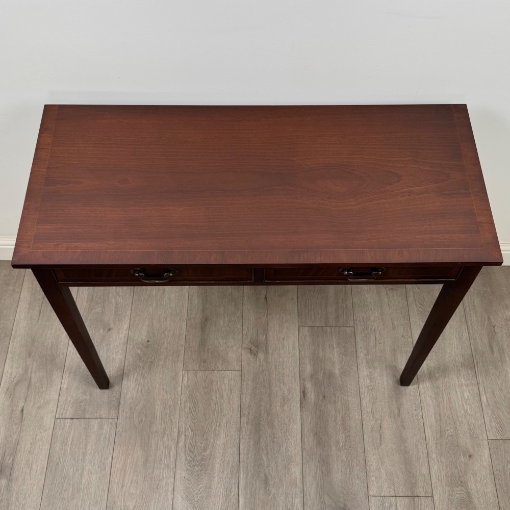 A dark mahogany writing table featuring two frieze drawers with brass swan-neck handles and tapered square legs. View IX