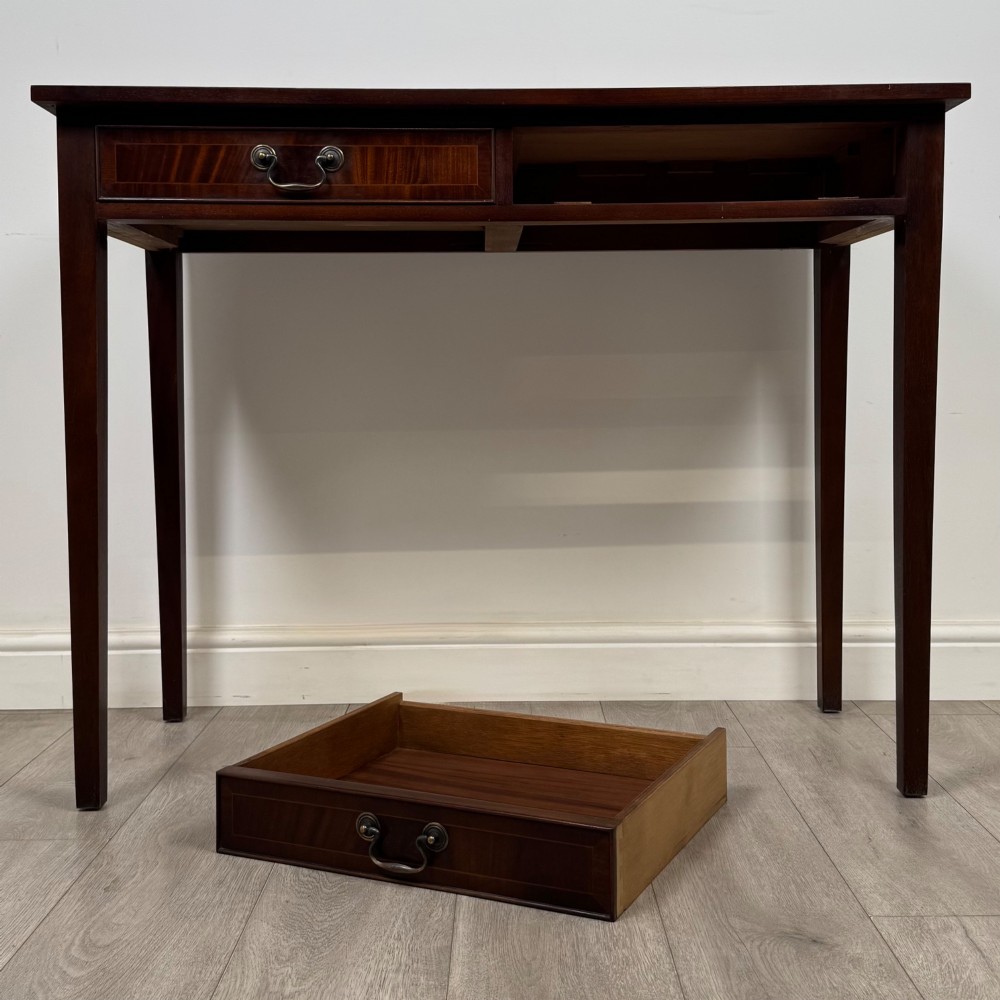 A dark mahogany writing table featuring two frieze drawers with brass swan-neck handles and tapered square legs. View X
