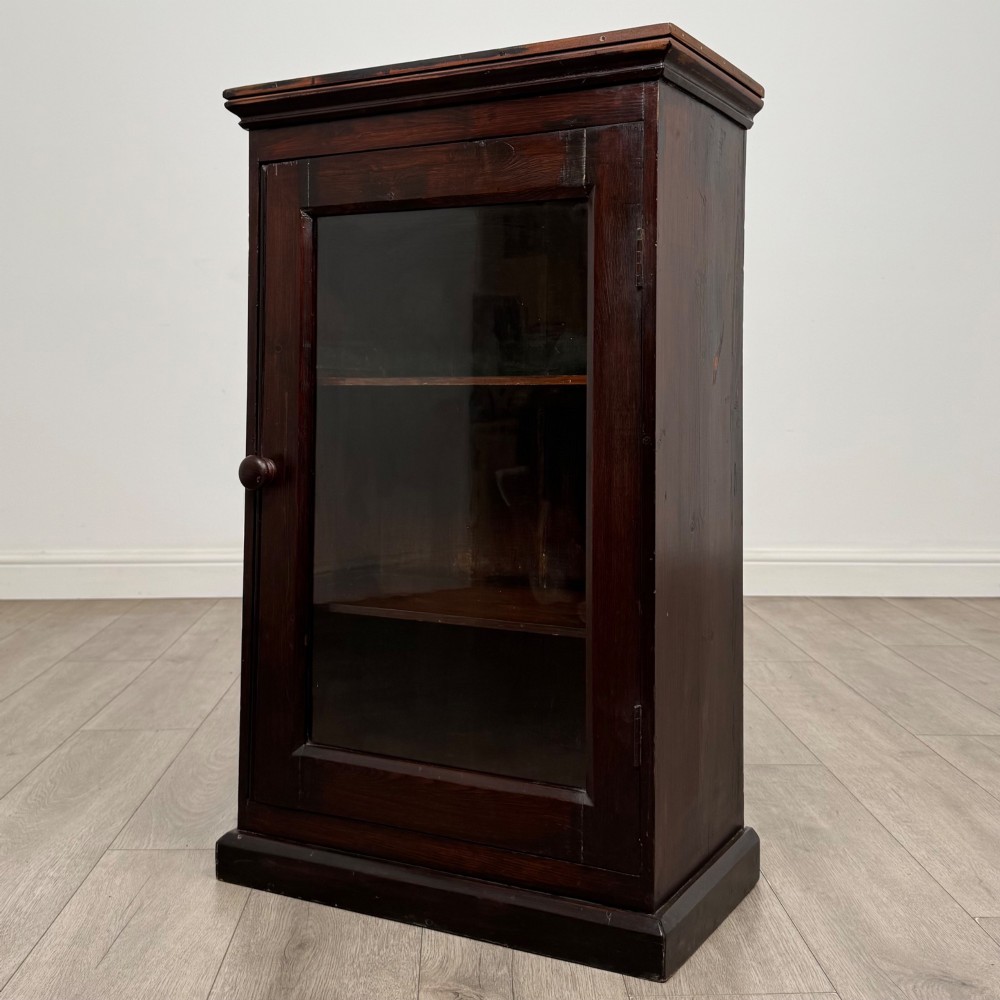 A dark brown stained Edwardian pine glazed cabinet featuring a single glass door with a turned wooden handle and internal shelves. View III