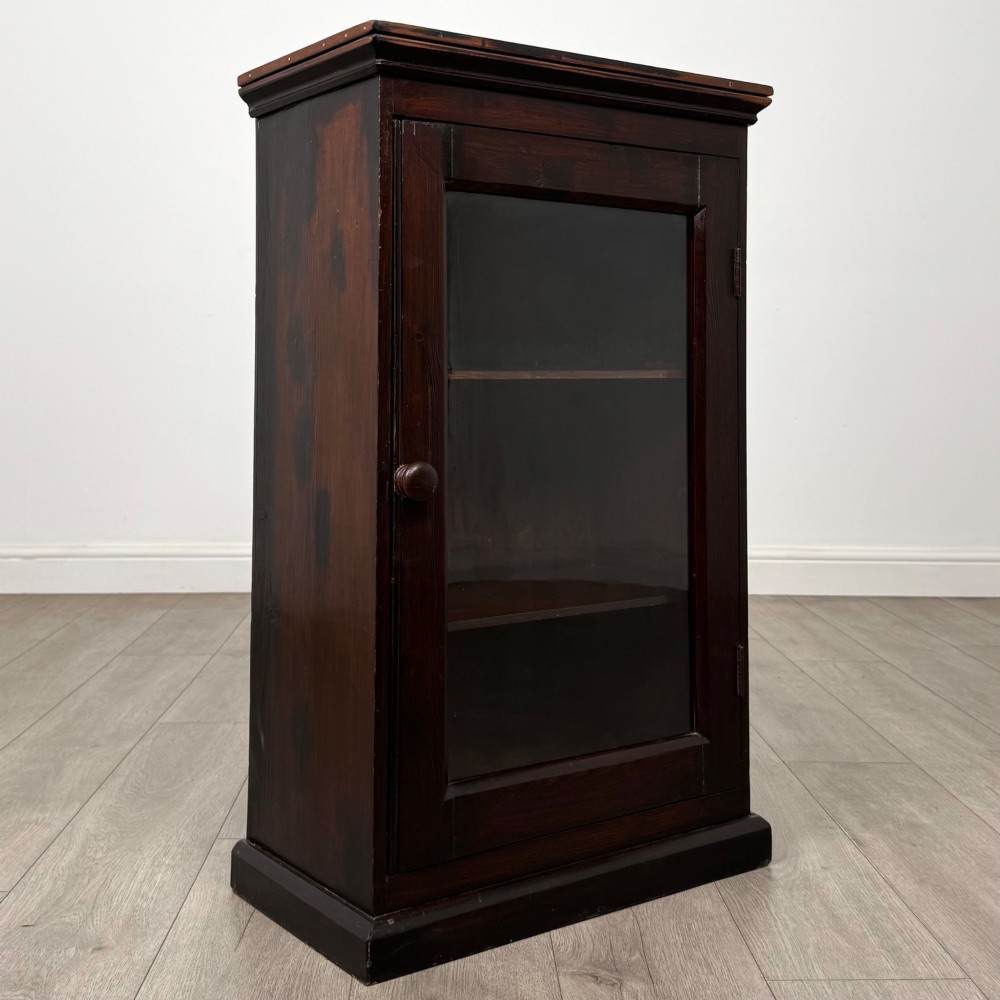 A dark brown stained Edwardian pine glazed cabinet featuring a single glass door with a turned wooden handle and internal shelves. View IX