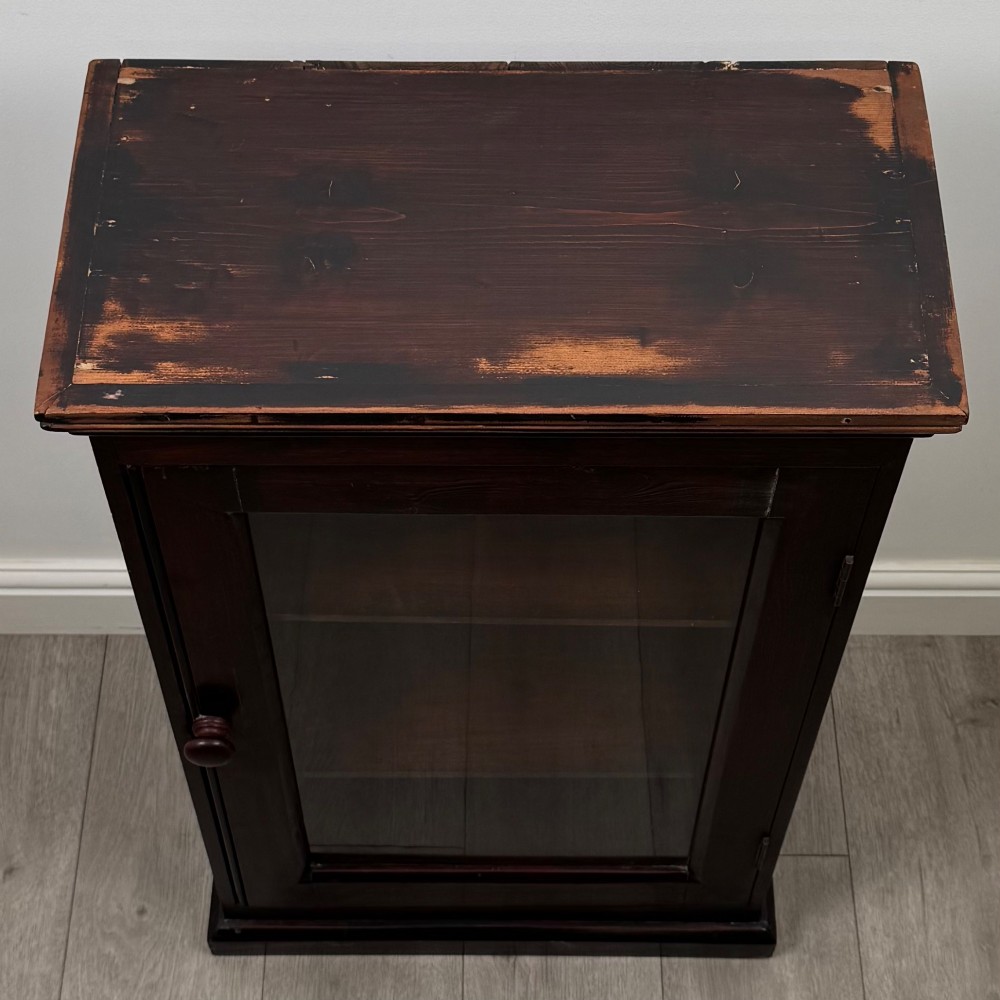 A dark brown stained Edwardian pine glazed cabinet featuring a single glass door with a turned wooden handle and internal shelves. View X
