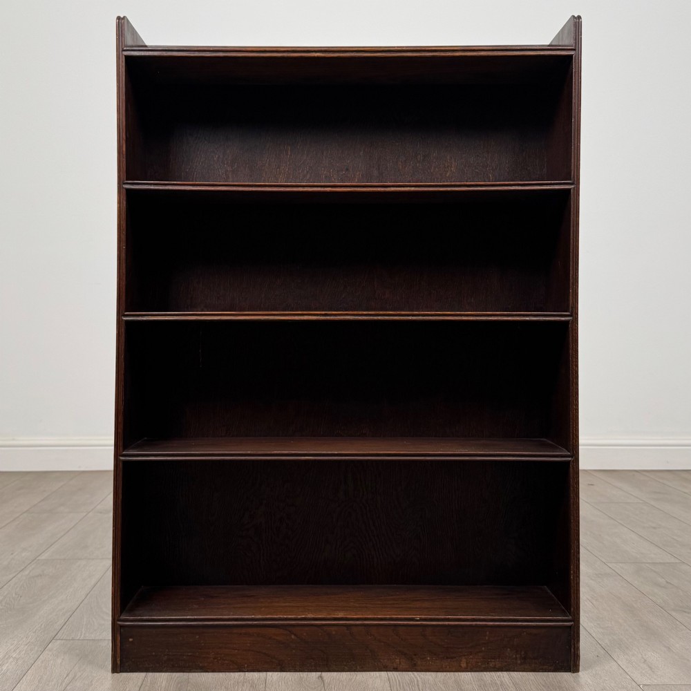An antique dark oak open bookcase featuring four horizontal shelves with raised side galleries and a solid plinth base. View II