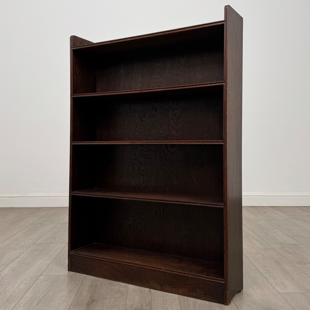 An antique dark oak open bookcase featuring four horizontal shelves with raised side galleries and a solid plinth base. View III