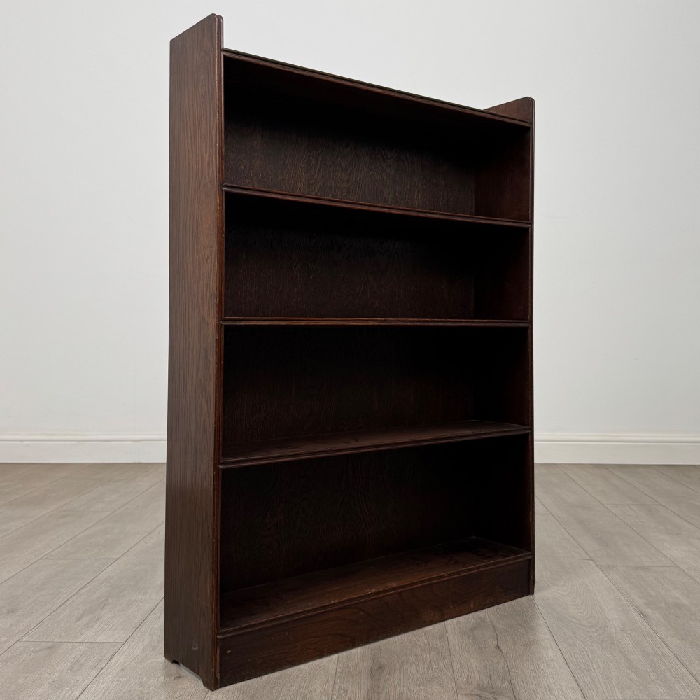 An antique dark oak open bookcase featuring four horizontal shelves with raised side galleries and a solid plinth base. View IX