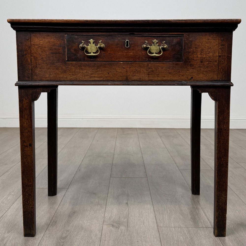 An 18th-century Georgian oak side table featuring a single frieze drawer with brass handles and straight square legs.