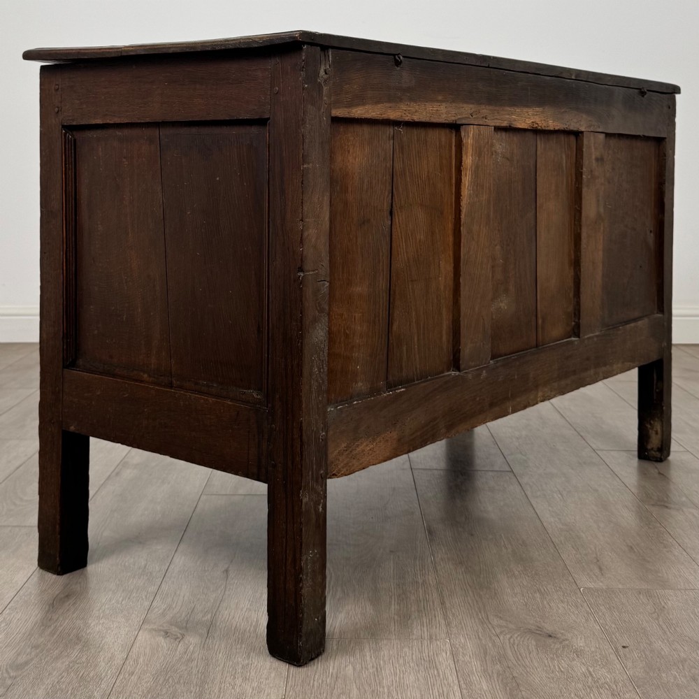 An 18th-century dark oak coffer featuring three sunken front panels, raised stiles, a hinged lid, and a central brass keyhole escutcheon. View IV