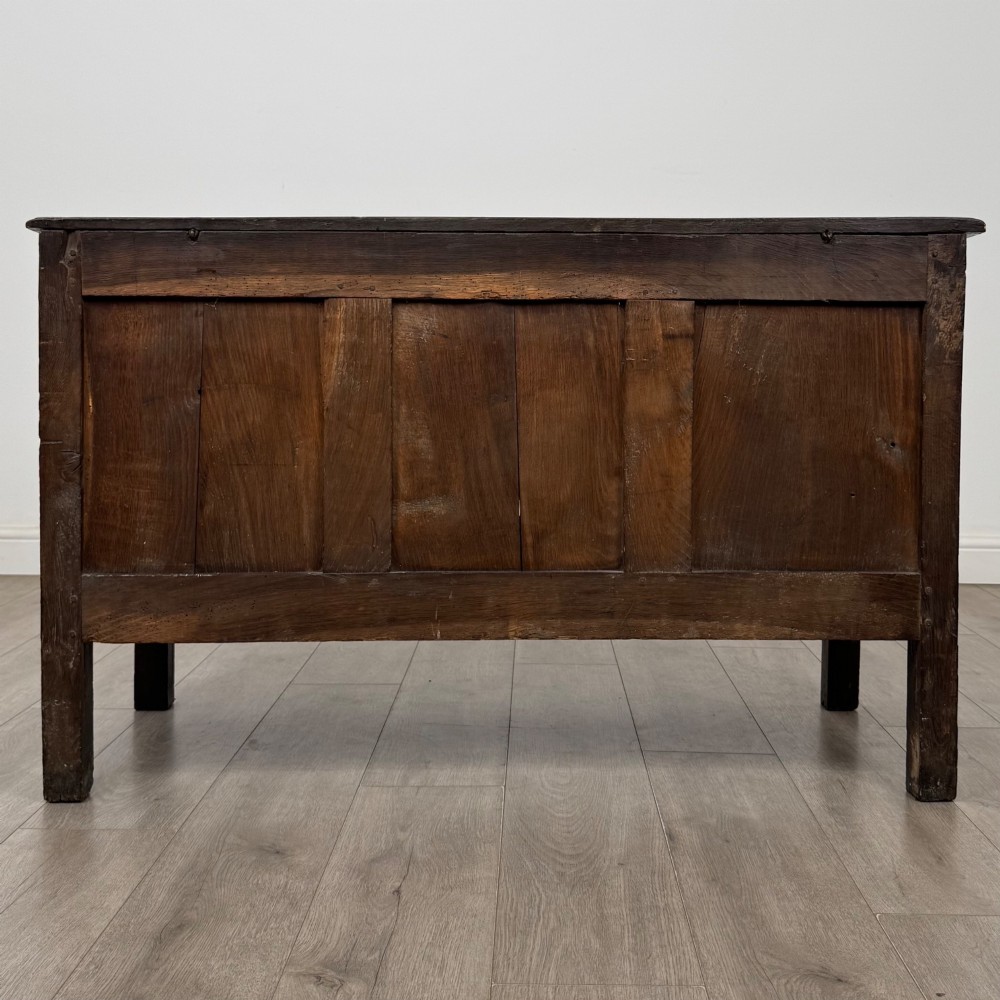 An 18th-century dark oak coffer featuring three sunken front panels, raised stiles, a hinged lid, and a central brass keyhole escutcheon. View V
