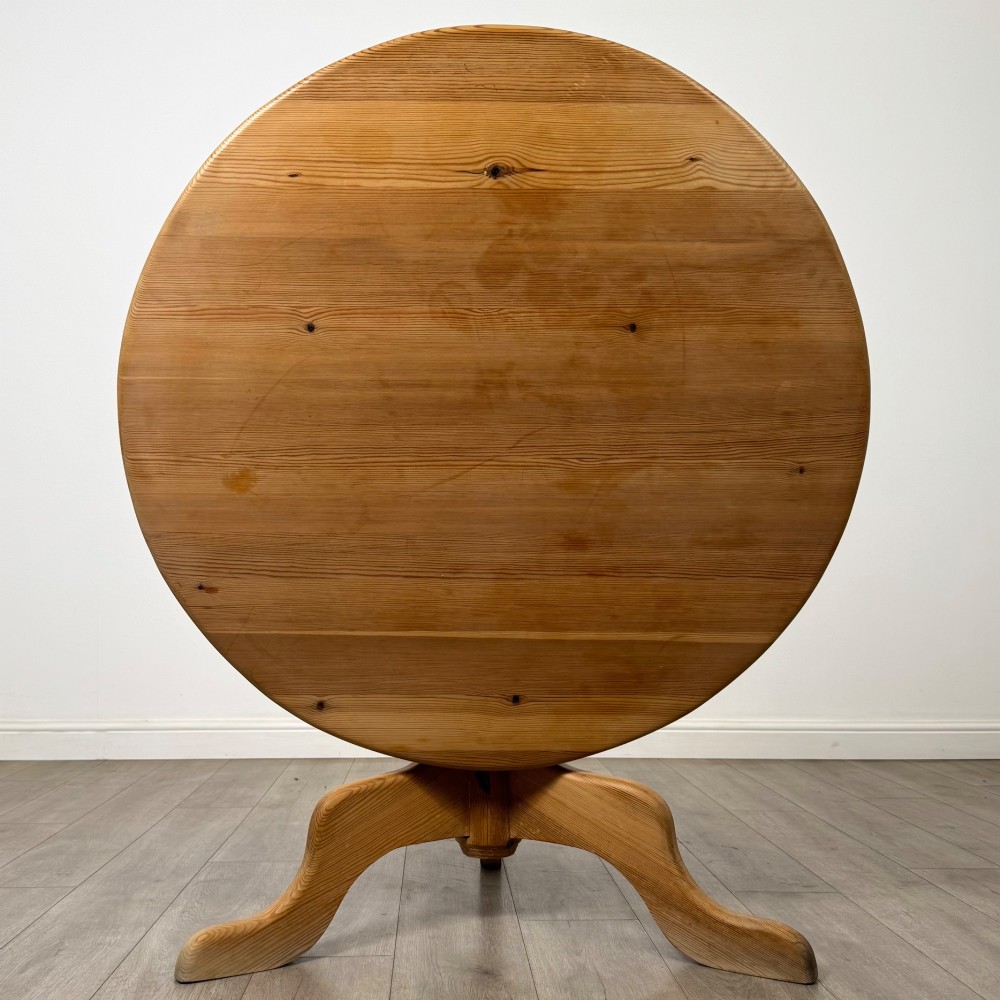 A 19th-century circular pine tilt-top breakfast table with a turned central pedestal column and splayed four-leg base. View II
