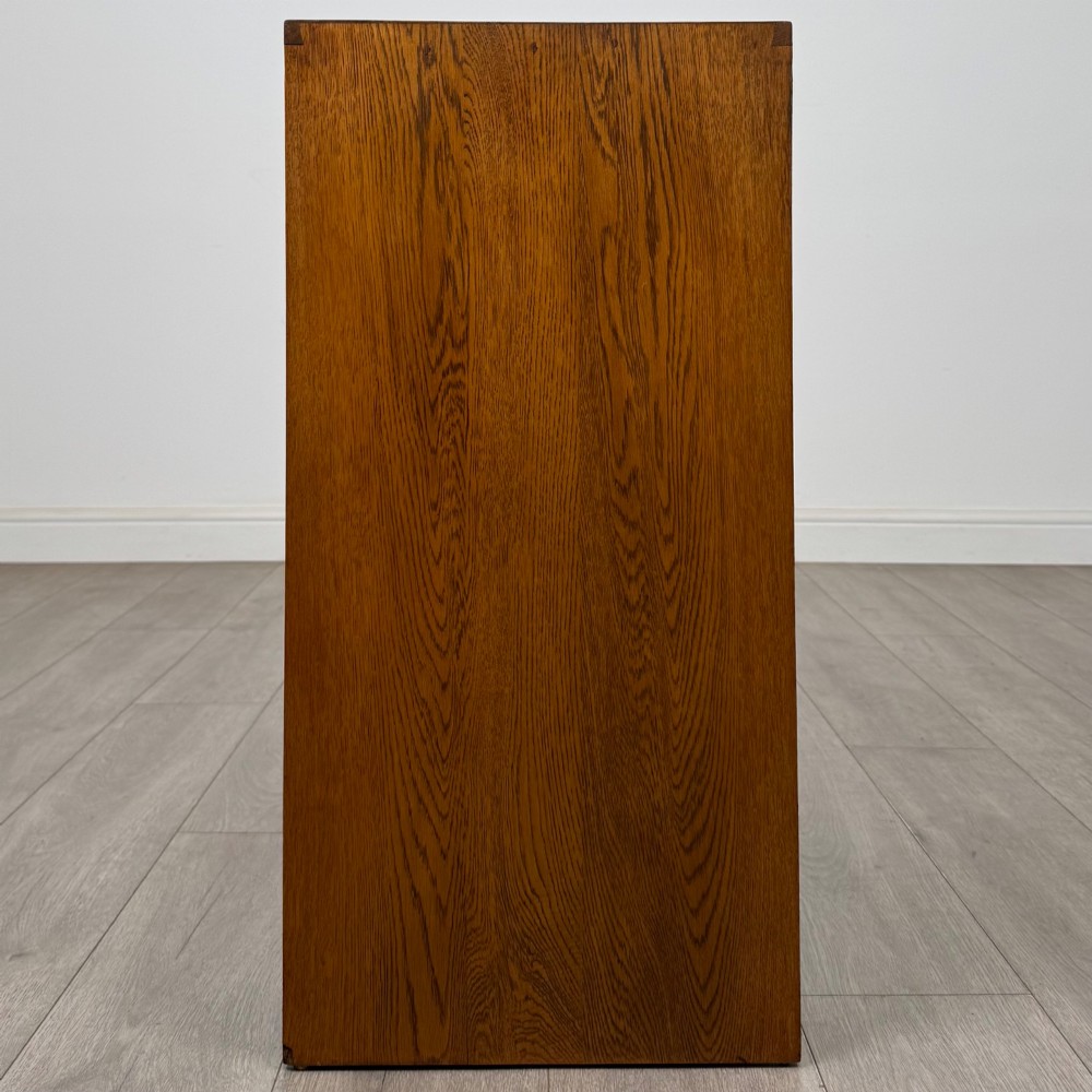 A freestanding golden oak cupboard featuring two flush rectangular doors with matching wooden block handles and brass hinges. View IV