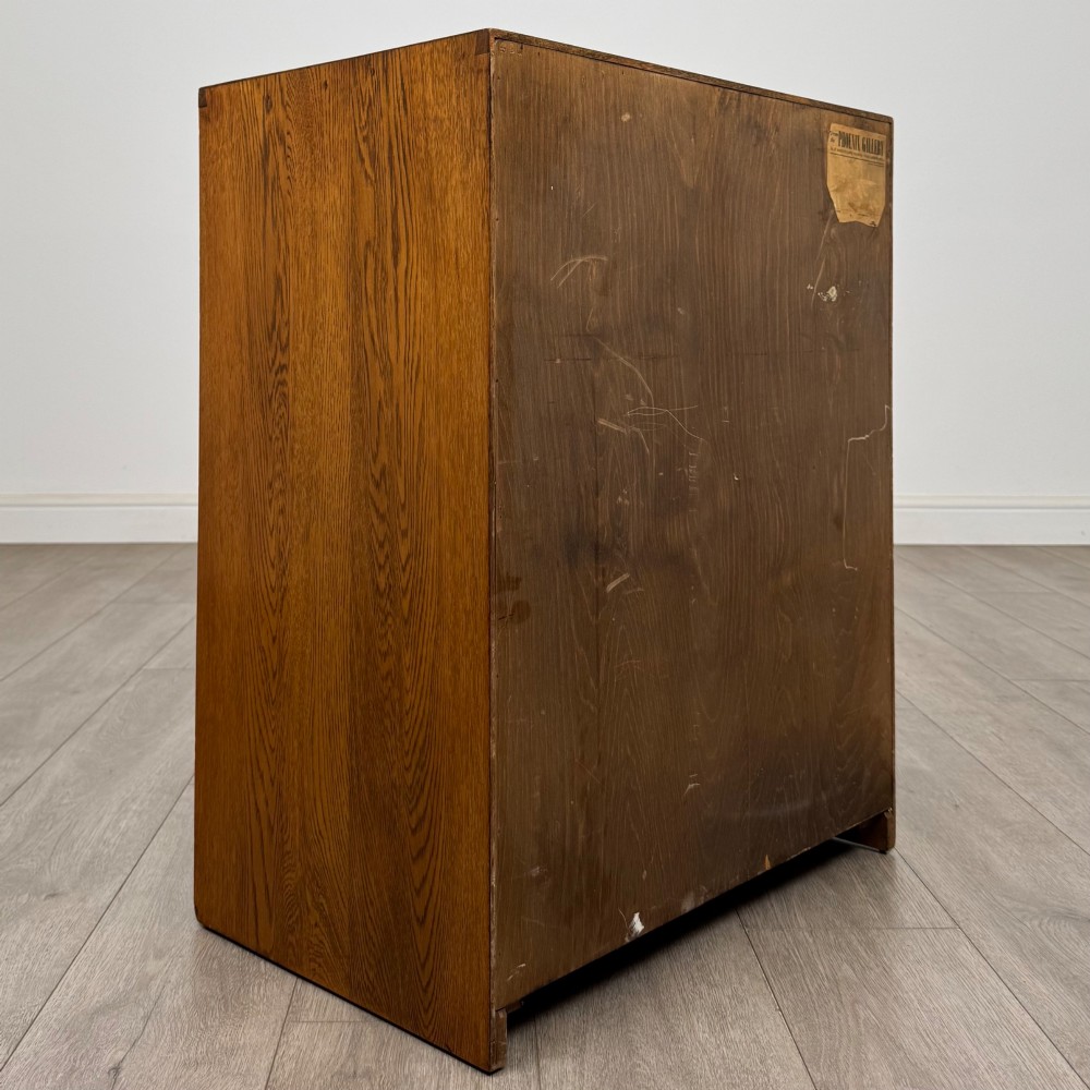A freestanding golden oak cupboard featuring two flush rectangular doors with matching wooden block handles and brass hinges. View V