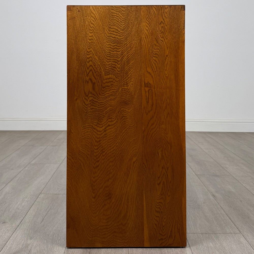 A freestanding golden oak cupboard featuring two flush rectangular doors with matching wooden block handles and brass hinges. View VIII