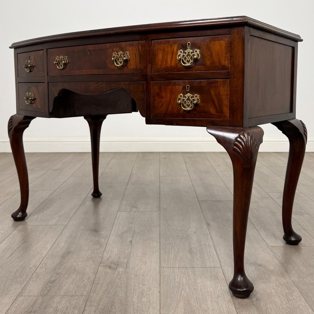 An Edwardian mahogany writing table featuring five drawers with decorative brass handles, a central kneehole apron, and carved cabriole legs. View II