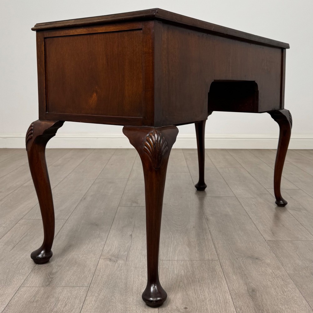 An Edwardian mahogany writing table featuring five drawers with decorative brass handles, a central kneehole apron, and carved cabriole legs. View IV
