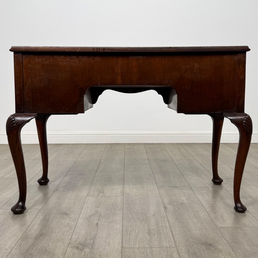 An Edwardian mahogany writing table featuring five drawers with decorative brass handles, a central kneehole apron, and carved cabriole legs. View V