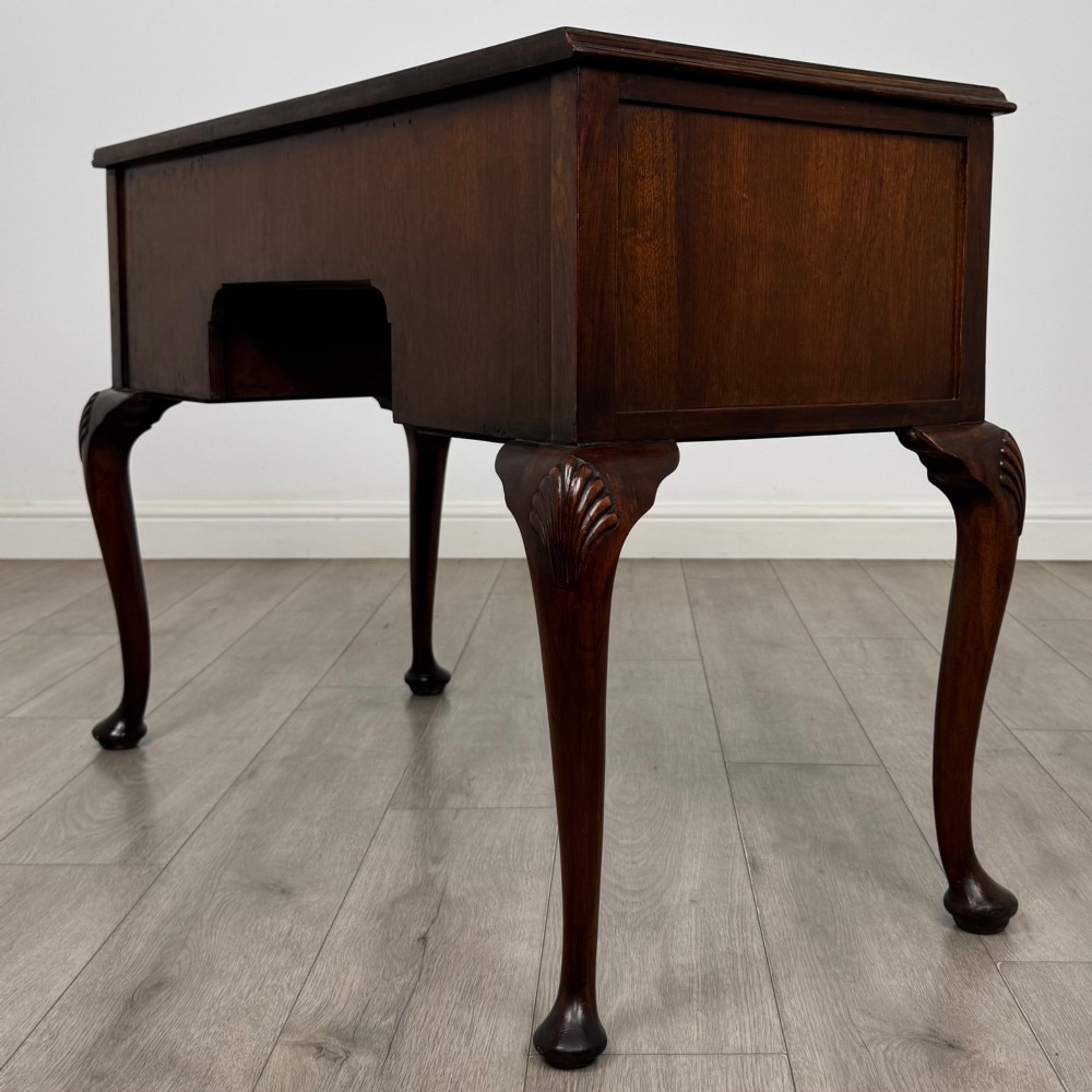 An Edwardian mahogany writing table featuring five drawers with decorative brass handles, a central kneehole apron, and carved cabriole legs. View VI