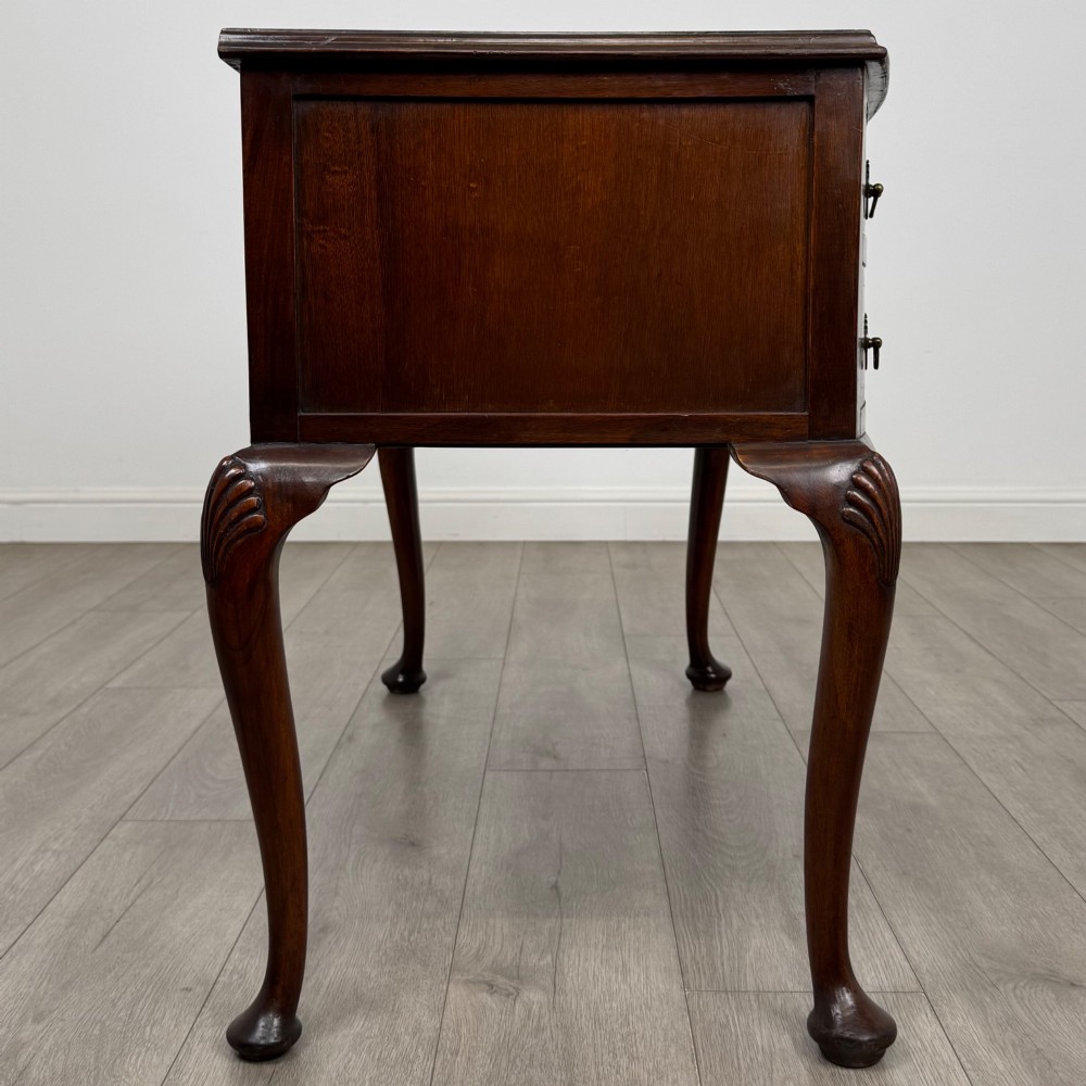 An Edwardian mahogany writing table featuring five drawers with decorative brass handles, a central kneehole apron, and carved cabriole legs. View VII