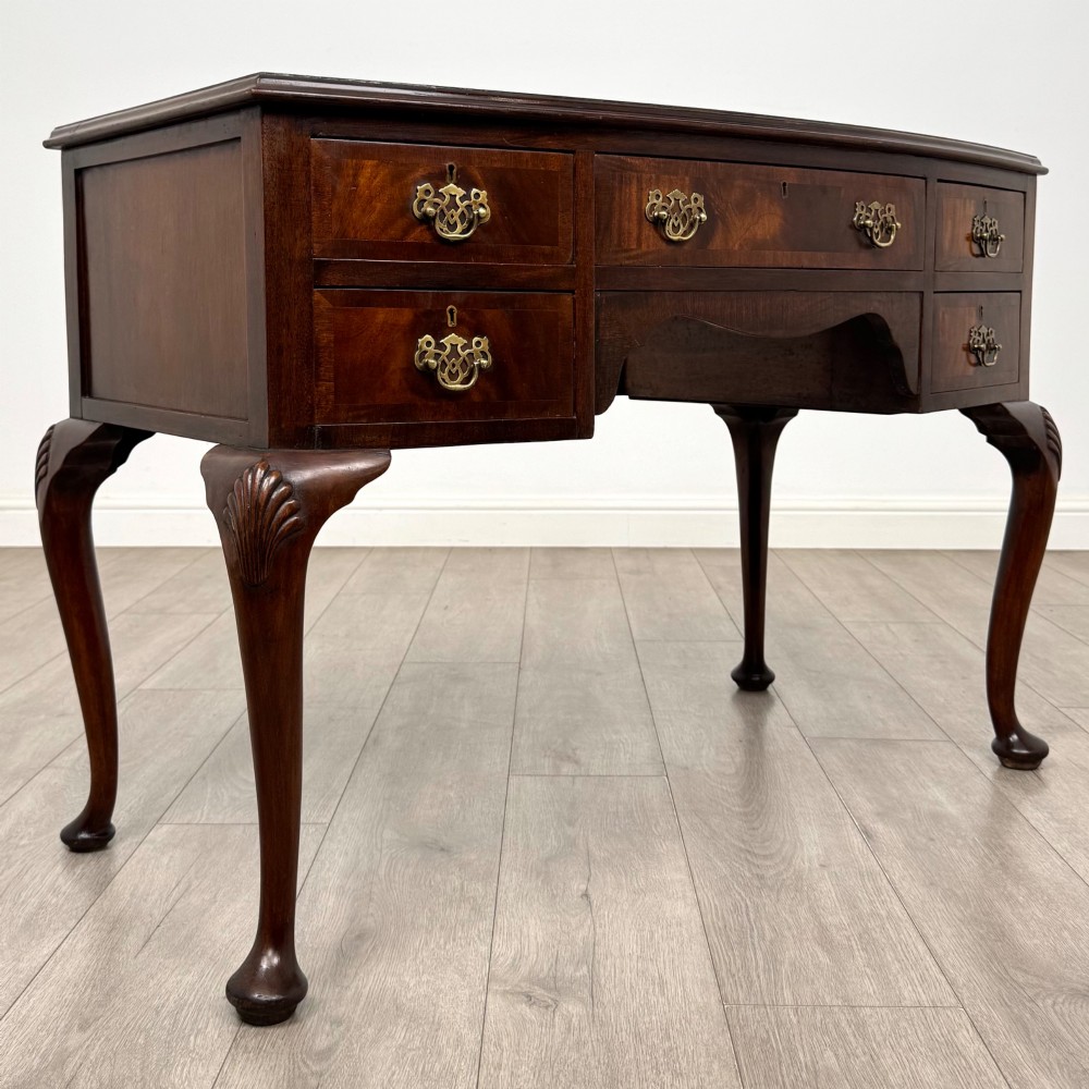 An Edwardian mahogany writing table featuring five drawers with decorative brass handles, a central kneehole apron, and carved cabriole legs. View VIII