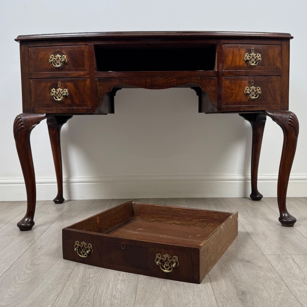An Edwardian mahogany writing table featuring five drawers with decorative brass handles, a central kneehole apron, and carved cabriole legs. View X