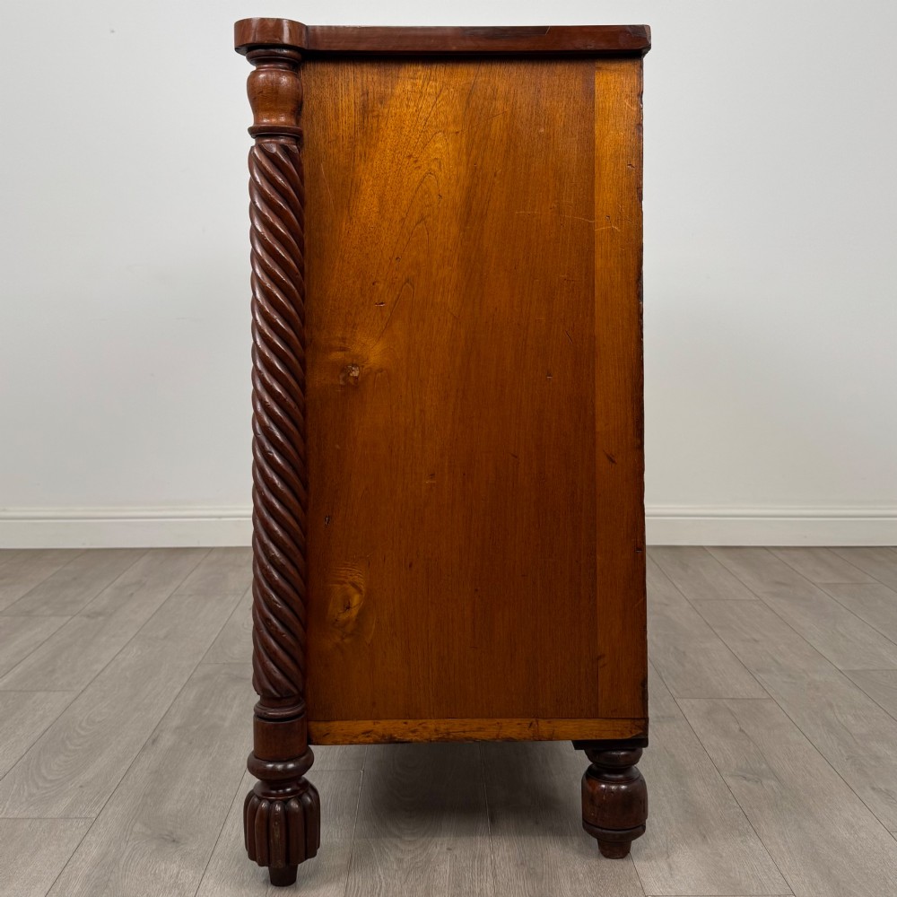 A 19th-century Regency mahogany chest of drawers featuring two short over three long graduated drawers, decorative spiral-twist side columns, glass knobs, and turned carved feet. View III