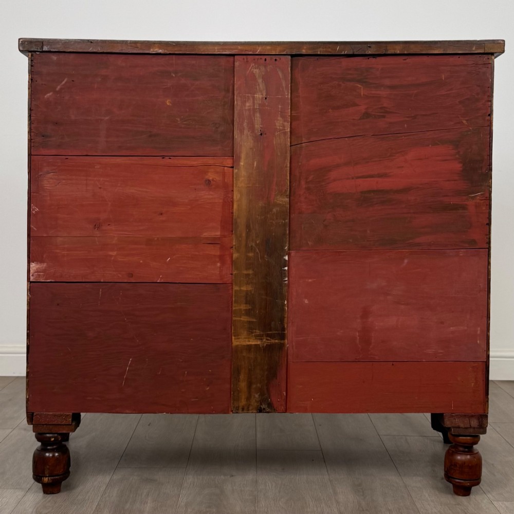 A 19th-century Regency mahogany chest of drawers featuring two short over three long graduated drawers, decorative spiral-twist side columns, glass knobs, and turned carved feet. View V