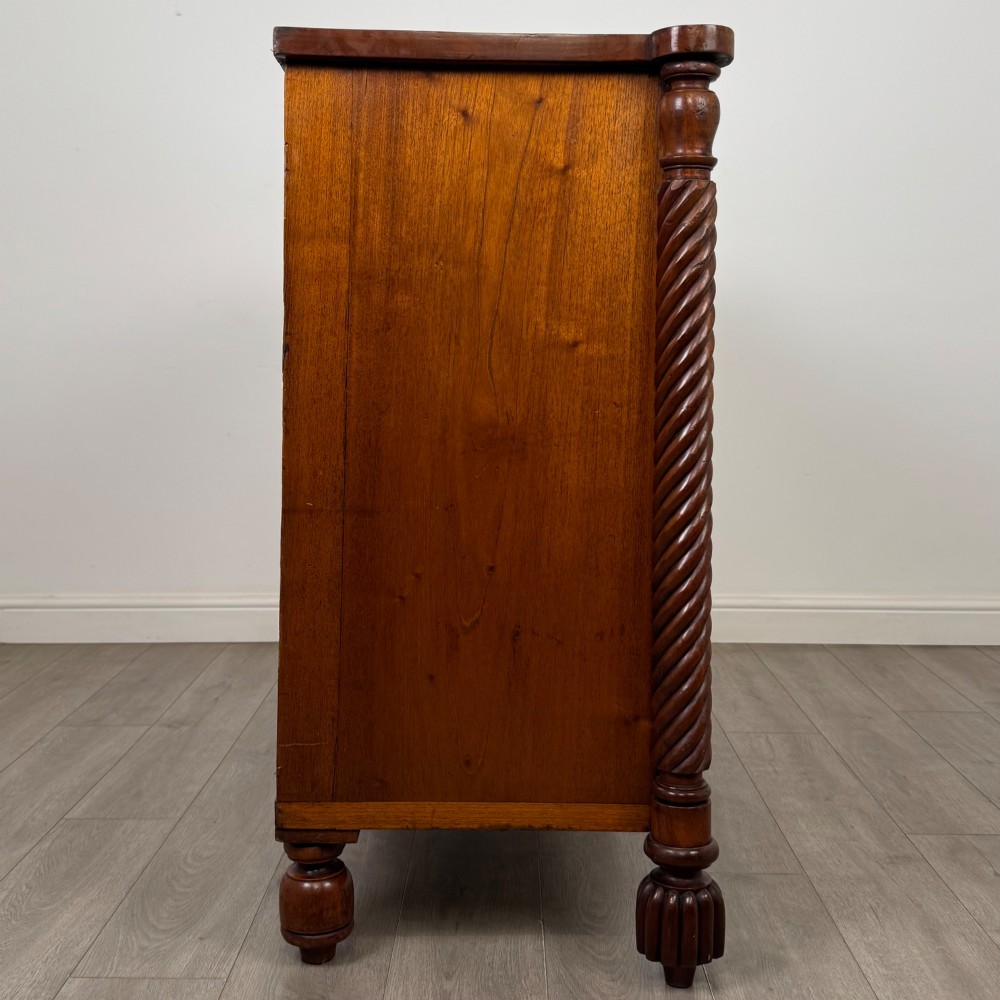 A 19th-century Regency mahogany chest of drawers featuring two short over three long graduated drawers, decorative spiral-twist side columns, glass knobs, and turned carved feet. View VII