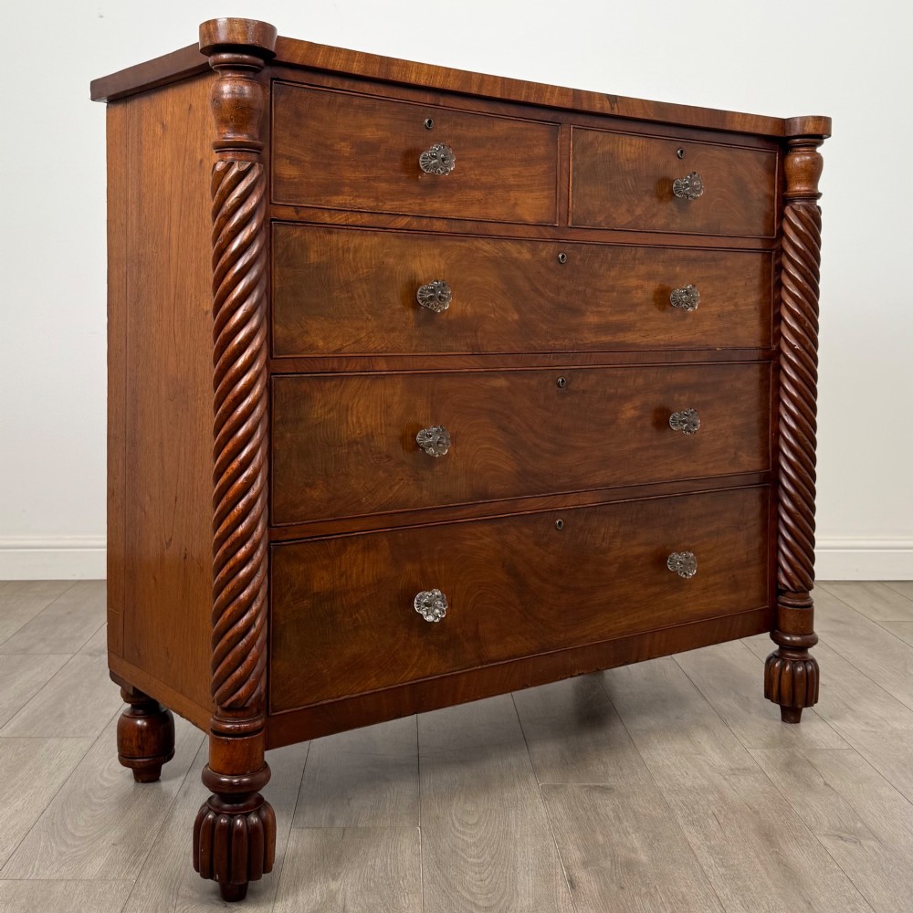 A 19th-century Regency mahogany chest of drawers featuring two short over three long graduated drawers, decorative spiral-twist side columns, glass knobs, and turned carved feet. View VIII