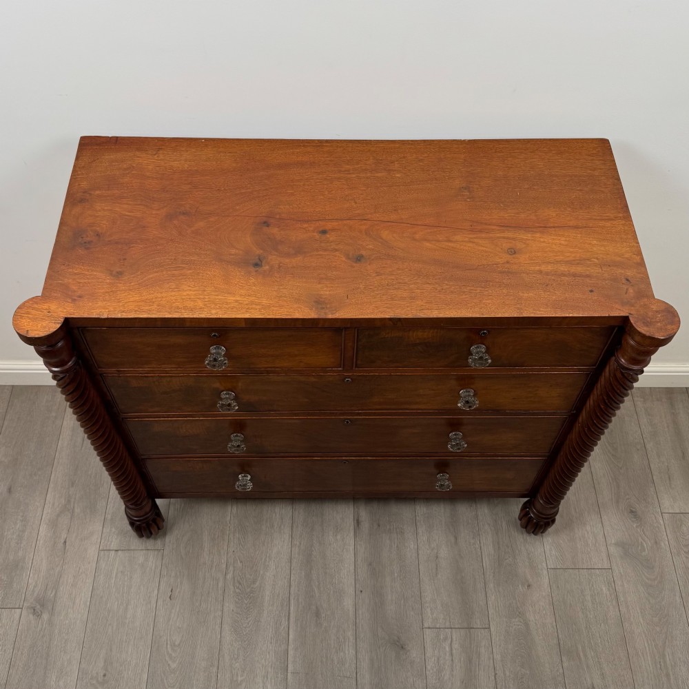 A 19th-century Regency mahogany chest of drawers featuring two short over three long graduated drawers, decorative spiral-twist side columns, glass knobs, and turned carved feet. View IX