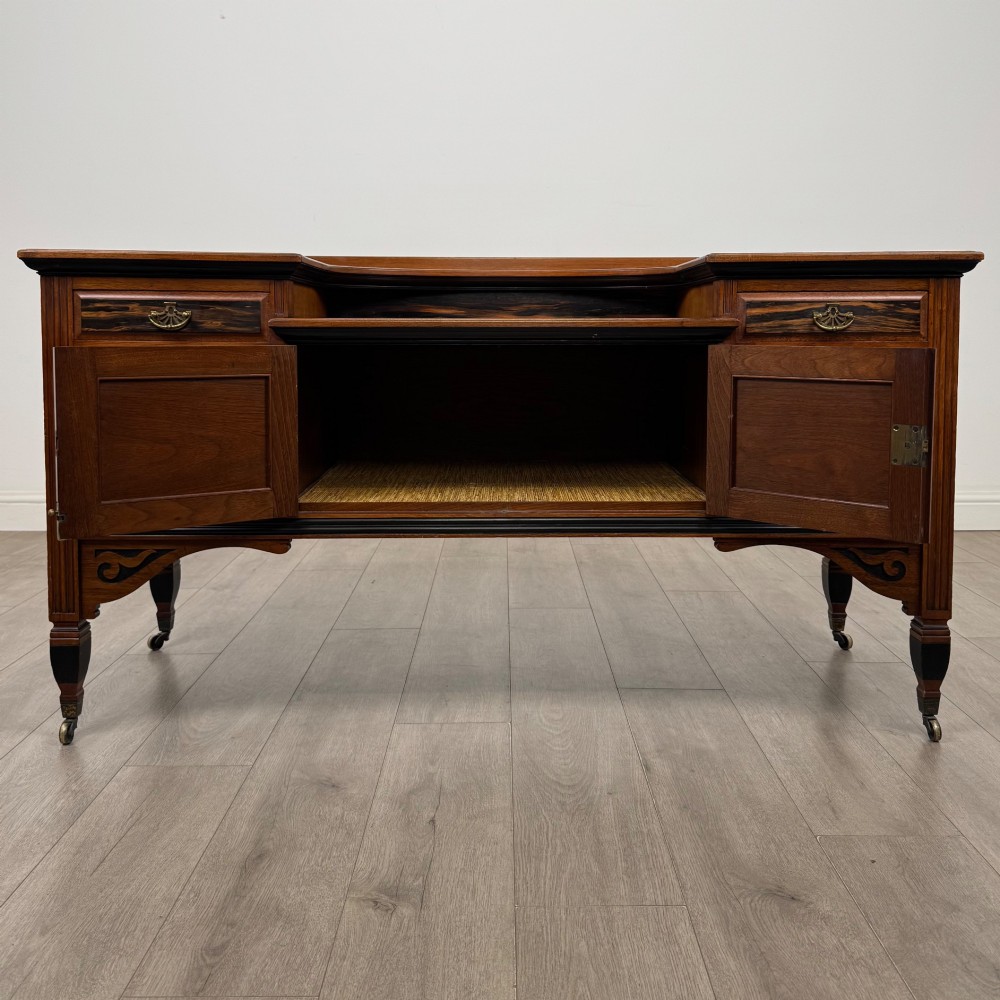 An antique mahogany low sideboard featuring six drawers, a central double cupboard, highly figured veneer panels, brass handles, and turned legs on castors. View II
