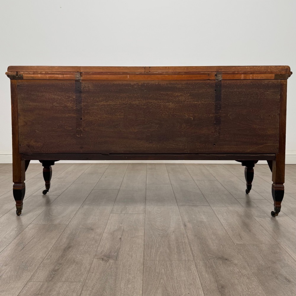 An antique mahogany low sideboard featuring six drawers, a central double cupboard, highly figured veneer panels, brass handles, and turned legs on castors. View VI