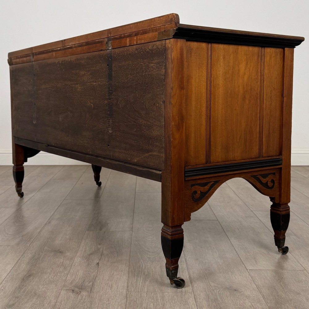 An antique mahogany low sideboard featuring six drawers, a central double cupboard, highly figured veneer panels, brass handles, and turned legs on castors. View VII