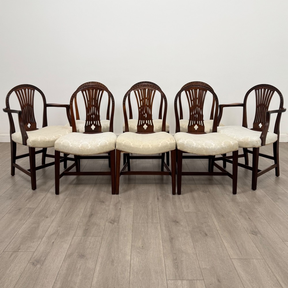 A set of eight 19th-century Hepplewhite style mahogany dining chairs featuring carved openwork back splats, square tapered legs, and light cream upholstered seats.
