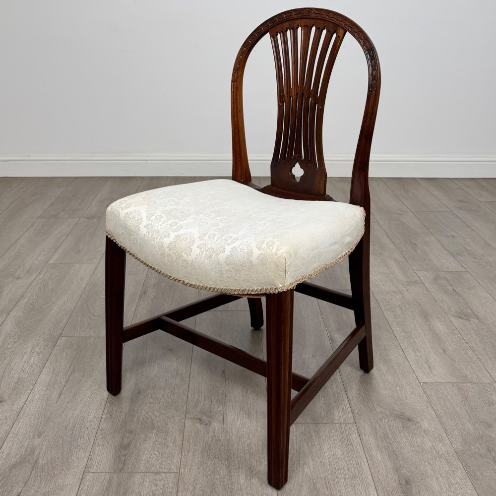 A set of eight 19th-century Hepplewhite style mahogany dining chairs featuring carved openwork back splats, square tapered legs, and light cream upholstered seats. View III