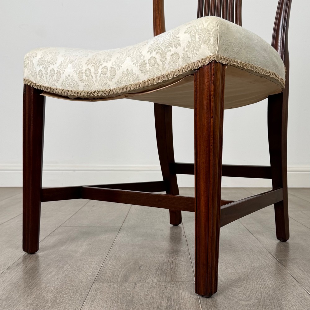 A set of eight 19th-century Hepplewhite style mahogany dining chairs featuring carved openwork back splats, square tapered legs, and light cream upholstered seats. View VI