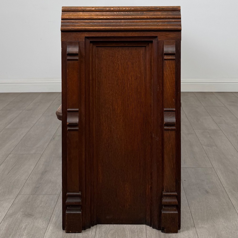 A long nineteenth-century oak church pew featuring a panelled back, moulded end supports, and a single solid wood bench seat. View III