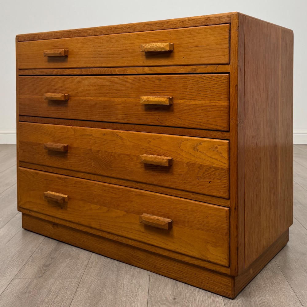 A golden oak chest of four full-width drawers featuring wooden bar handles and a solid plinth base. View II