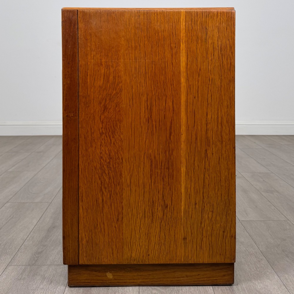 A golden oak chest of four full-width drawers featuring wooden bar handles and a solid plinth base. View III