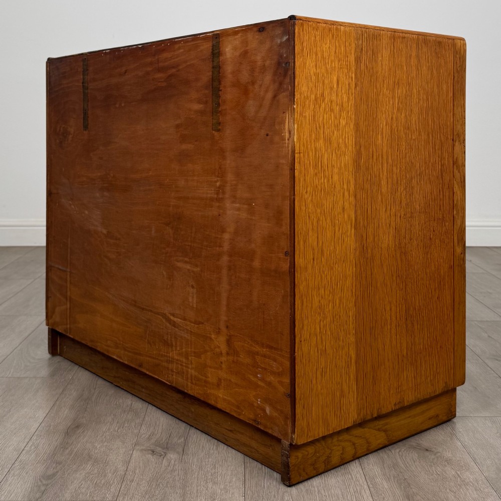 A golden oak chest of four full-width drawers featuring wooden bar handles and a solid plinth base. View VI