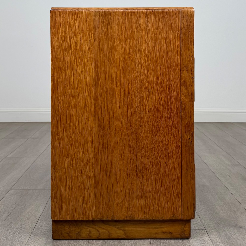A golden oak chest of four full-width drawers featuring wooden bar handles and a solid plinth base. View VII