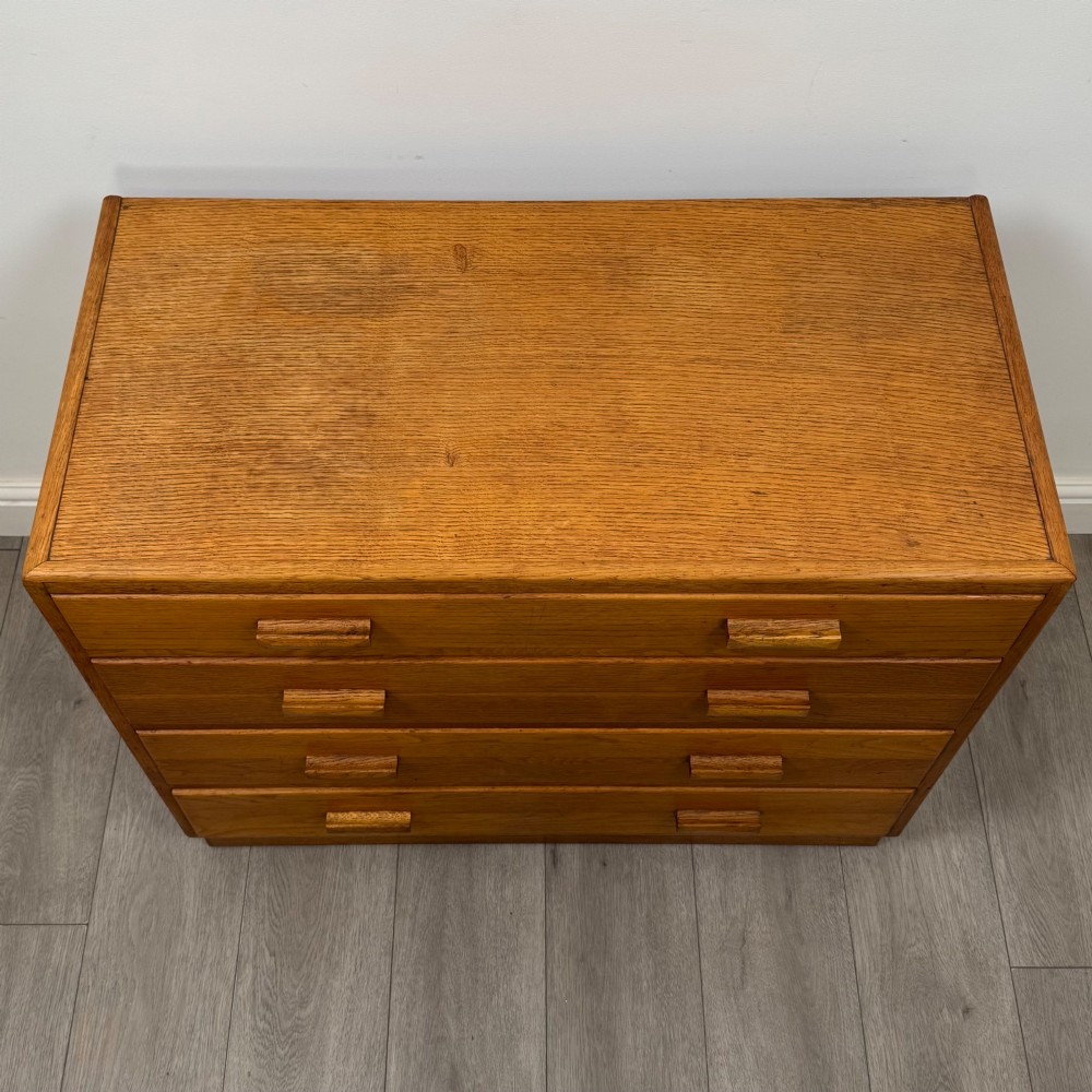 A golden oak chest of four full-width drawers featuring wooden bar handles and a solid plinth base. View IX