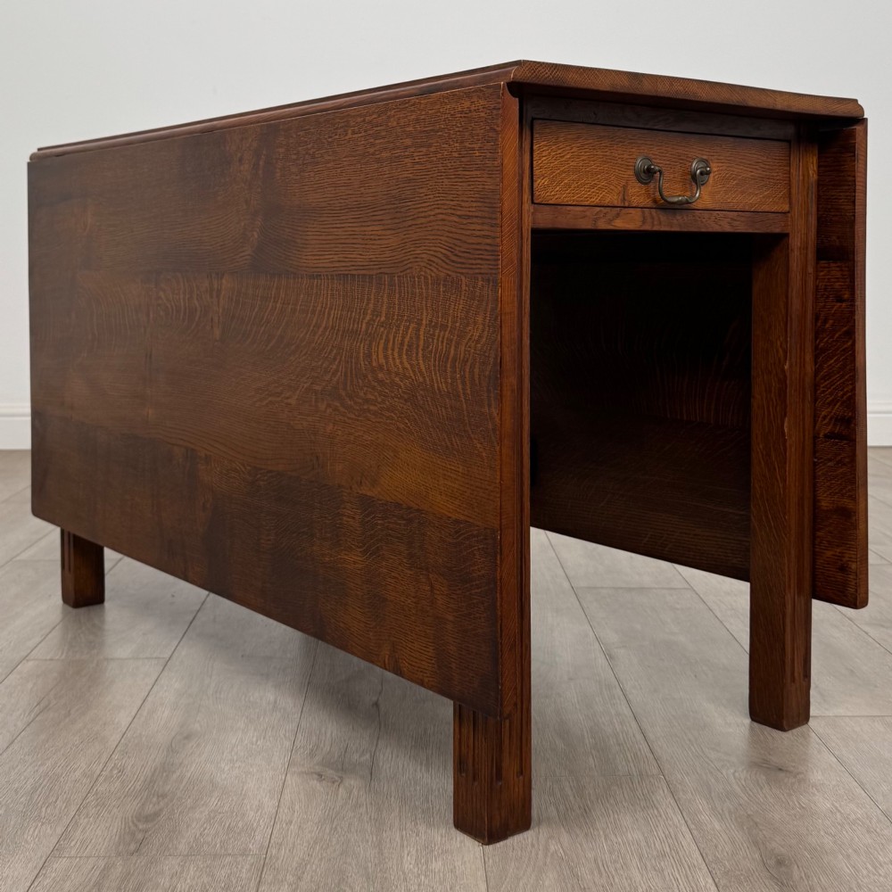 A 20th-century oak drop-leaf table shown with lowered flaps, featuring a single end drawer with a brass drop handle and square legs. View III
