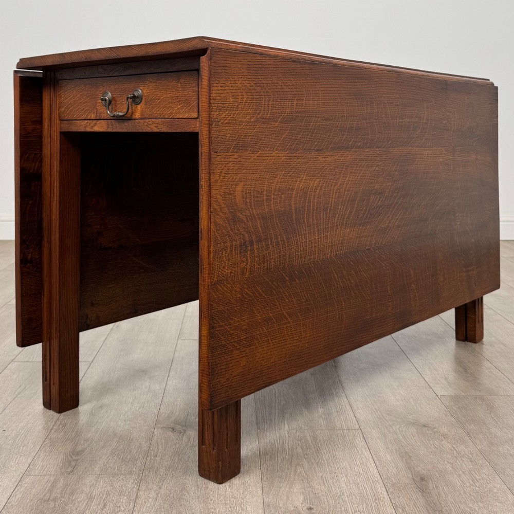 A 20th-century oak drop-leaf table shown with lowered flaps, featuring a single end drawer with a brass drop handle and square legs. View VI