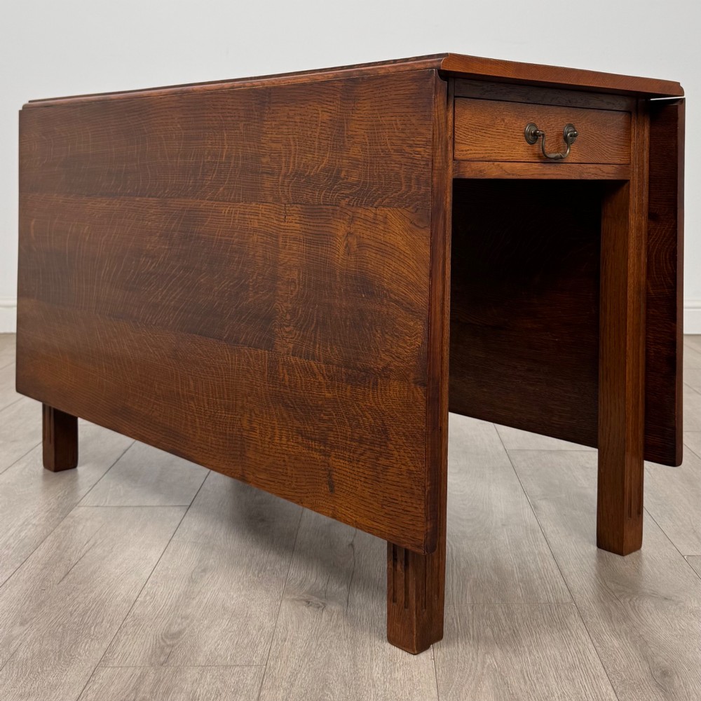 A 20th-century oak drop-leaf table shown with lowered flaps, featuring a single end drawer with a brass drop handle and square legs. View VIII